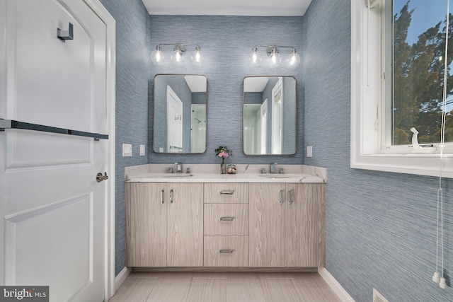 bathroom featuring double vanity, baseboards, and a sink