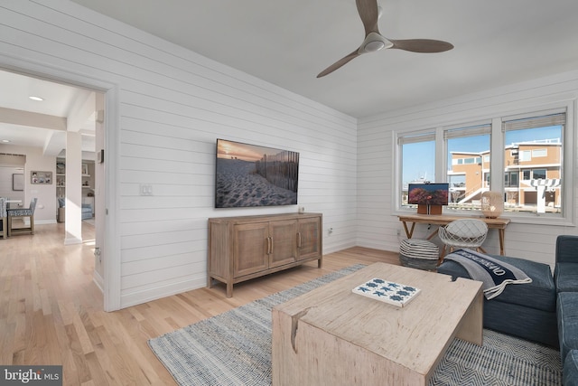 living area featuring ceiling fan, light wood-style flooring, and baseboards