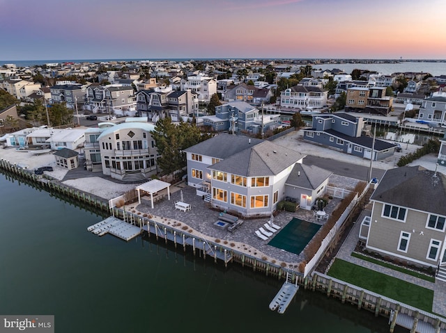 aerial view at dusk with a residential view and a water view