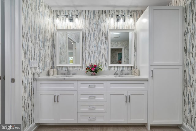 full bathroom with double vanity, a sink, and wallpapered walls