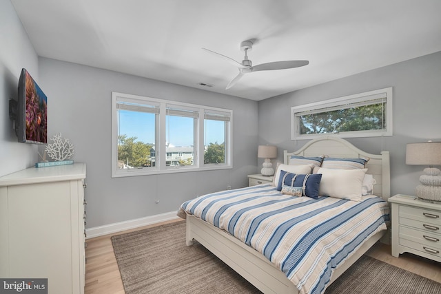 bedroom featuring visible vents, ceiling fan, baseboards, and wood finished floors