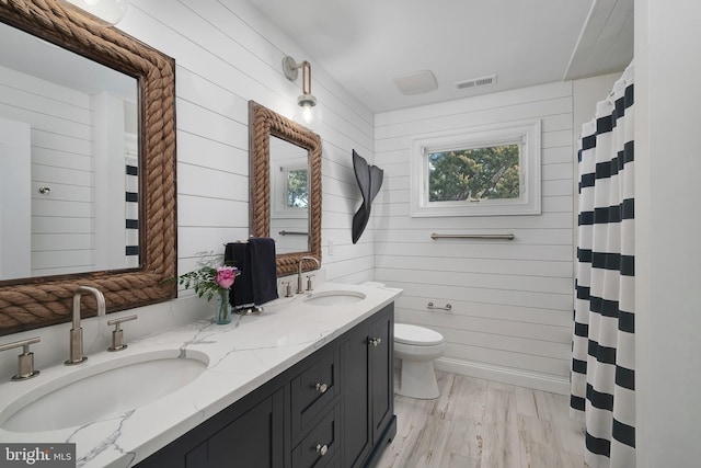 bathroom featuring toilet, double vanity, visible vents, and a sink