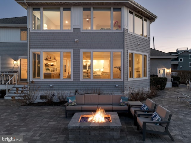 back of house at dusk with a patio area and an outdoor living space with a fire pit