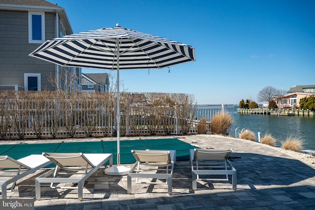 view of swimming pool featuring a patio area, a water view, and fence