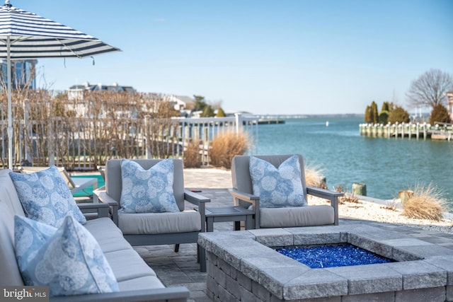 view of patio with a water view, fence, and an outdoor living space with a fire pit