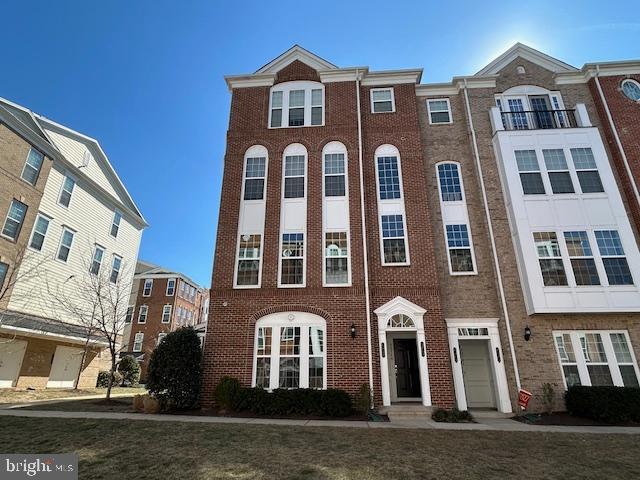 townhome / multi-family property with a garage, brick siding, and a front lawn