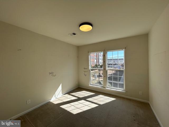 unfurnished room featuring carpet, visible vents, and baseboards