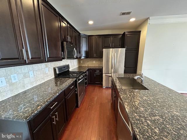 kitchen with visible vents, decorative backsplash, appliances with stainless steel finishes, dark wood-style flooring, and a sink