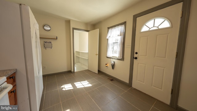 foyer entrance featuring visible vents, baseboards, an AC wall unit, and dark tile patterned floors