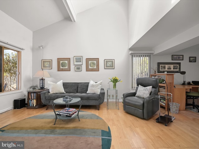 living room featuring high vaulted ceiling, hardwood / wood-style floors, beam ceiling, and baseboards