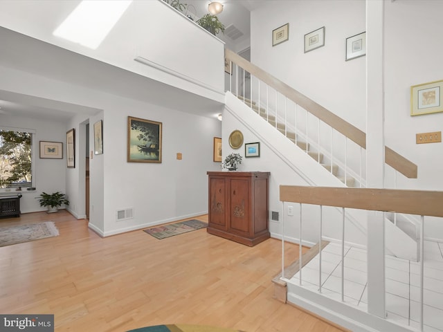 entrance foyer with visible vents, baseboards, radiator heating unit, stairway, and wood finished floors