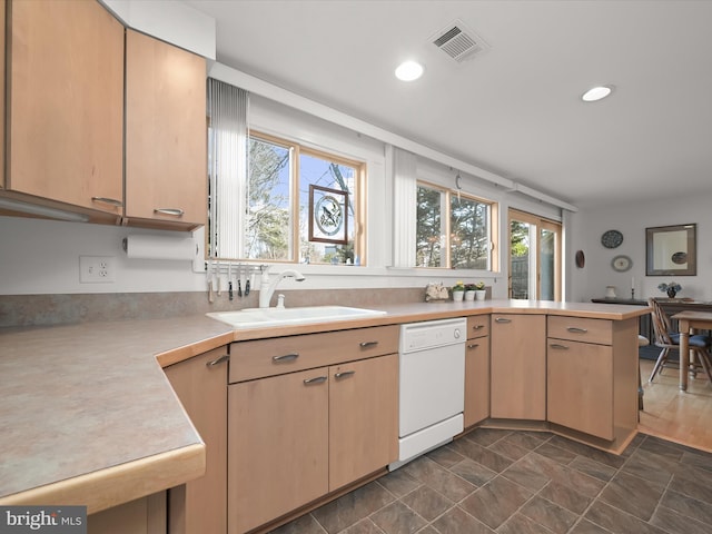 kitchen featuring light countertops, visible vents, white dishwasher, a sink, and a peninsula