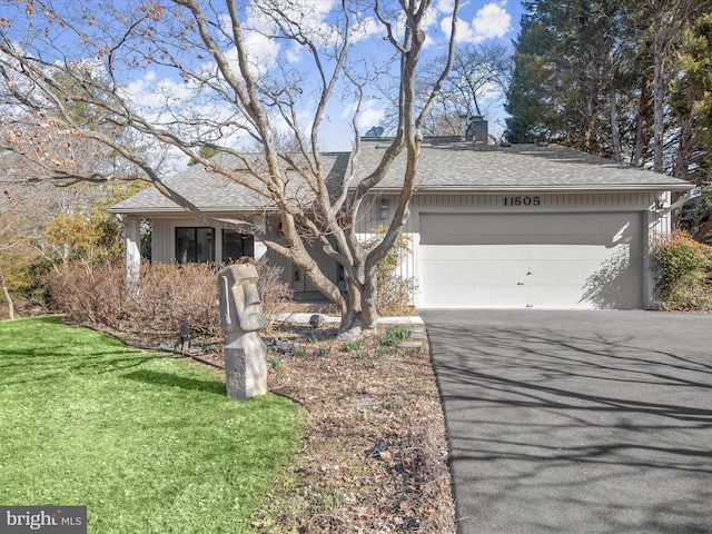 view of front of house featuring a garage, roof with shingles, aphalt driveway, and a chimney