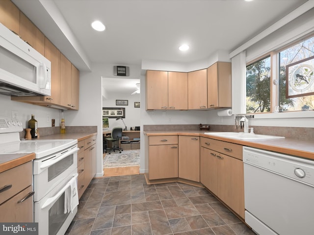 kitchen featuring white appliances, light countertops, light brown cabinets, a sink, and recessed lighting