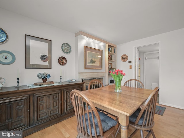 dining area featuring light wood-type flooring and a fireplace