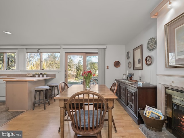 dining space featuring light wood-style floors and a glass covered fireplace