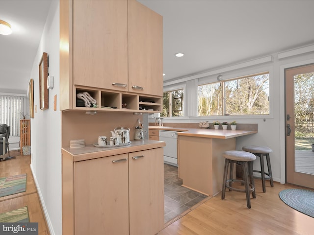 kitchen featuring light countertops, white dishwasher, light wood-style flooring, and open shelves