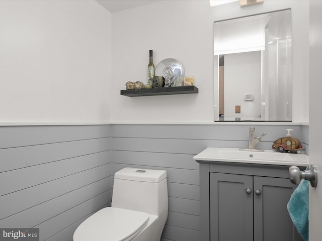 bathroom with toilet, vanity, and wainscoting