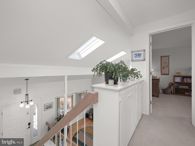 hallway with lofted ceiling with skylight, light colored carpet, and visible vents