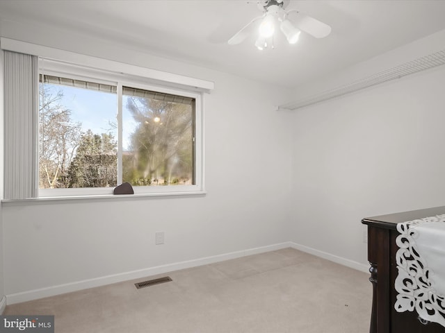 interior space featuring light carpet, ceiling fan, visible vents, and baseboards