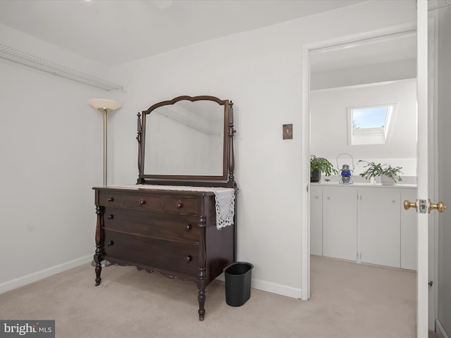 bedroom with light carpet, a skylight, and baseboards