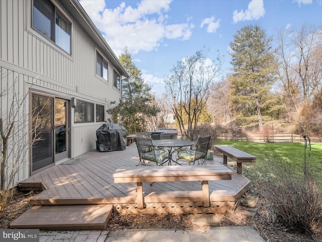 deck featuring a grill, outdoor dining area, and a lawn