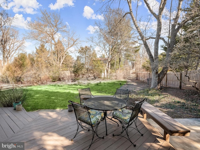 wooden terrace with outdoor dining area, a lawn, and fence