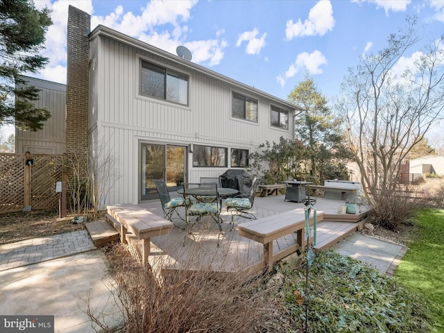 back of house featuring a deck, outdoor dining space, and a chimney