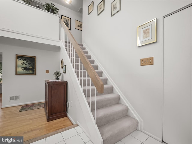 staircase with baseboards, visible vents, and wood finished floors