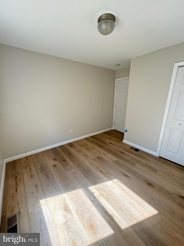 unfurnished bedroom featuring wood finished floors, visible vents, and baseboards