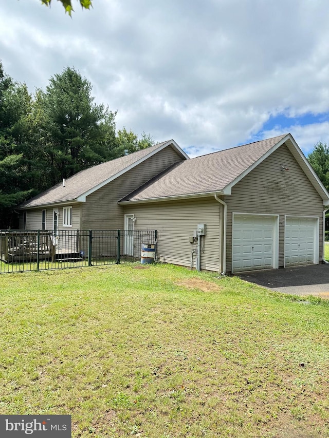 view of home's exterior featuring roof with shingles, a yard, an attached garage, and fence