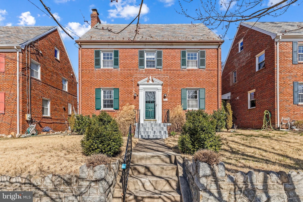 colonial-style house with brick siding and a chimney