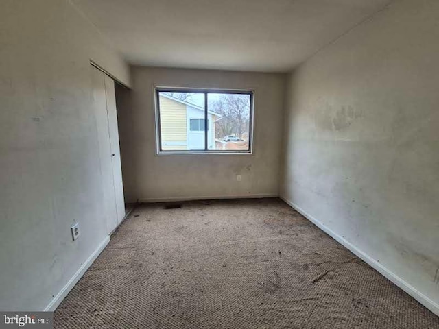 spare room featuring carpet and baseboards