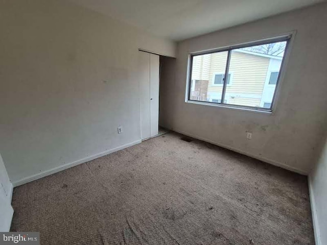 unfurnished bedroom featuring carpet floors, baseboards, and a closet