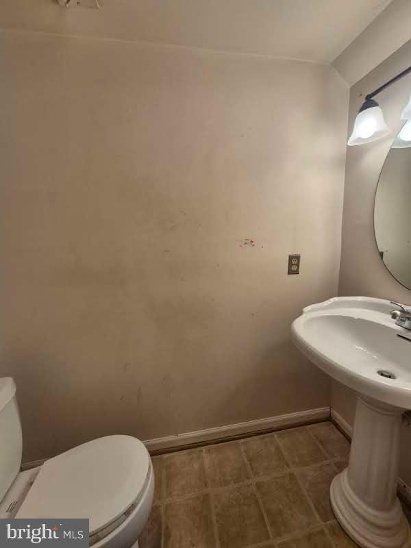 half bathroom featuring baseboards and toilet