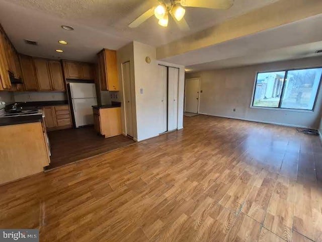 kitchen featuring dark wood-style floors, freestanding refrigerator, open floor plan, and dark countertops