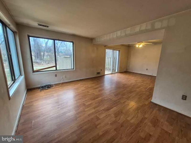 spare room featuring visible vents, ceiling fan, baseboards, and wood finished floors