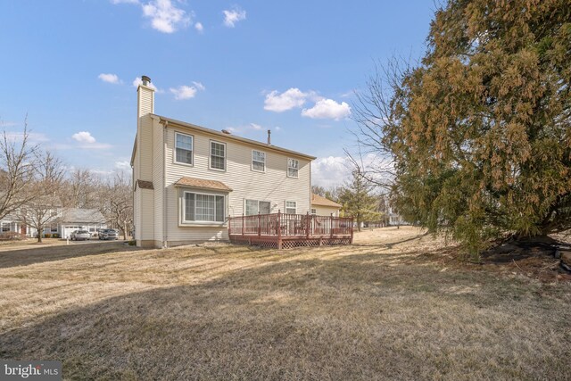 rear view of house featuring a yard, a chimney, and a wooden deck