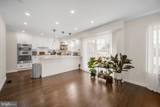 kitchen with double oven, white cabinetry, tasteful backsplash, and dark wood-type flooring