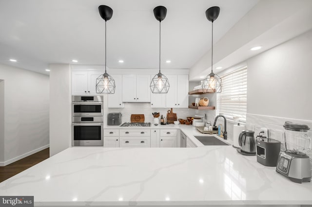 kitchen with appliances with stainless steel finishes, white cabinets, a sink, and open shelves