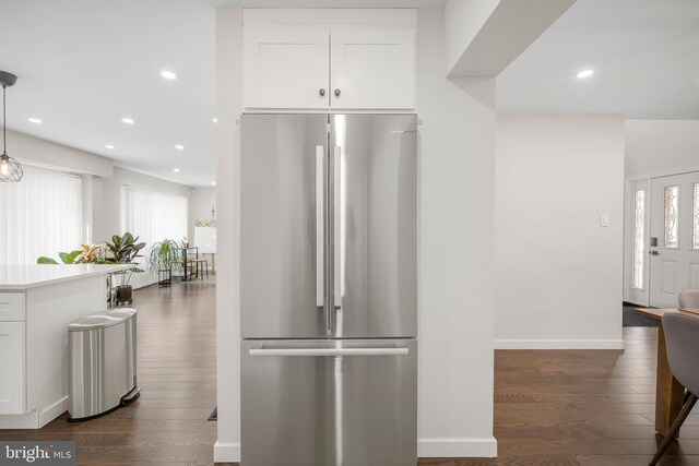 kitchen featuring dark wood-type flooring, freestanding refrigerator, white cabinetry, and plenty of natural light