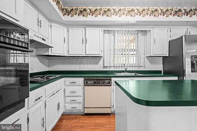 kitchen with electric cooktop, dark countertops, wood finished floors, oven, and a sink