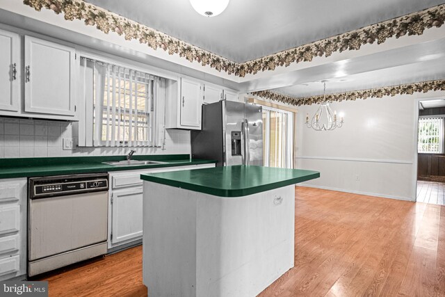 kitchen featuring light wood-style flooring, dark countertops, dishwasher, and stainless steel refrigerator with ice dispenser