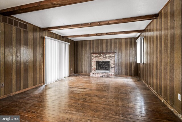 unfurnished living room with wood-type flooring, a fireplace, and beamed ceiling