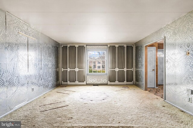 spare room featuring carpet floors and wallpapered walls