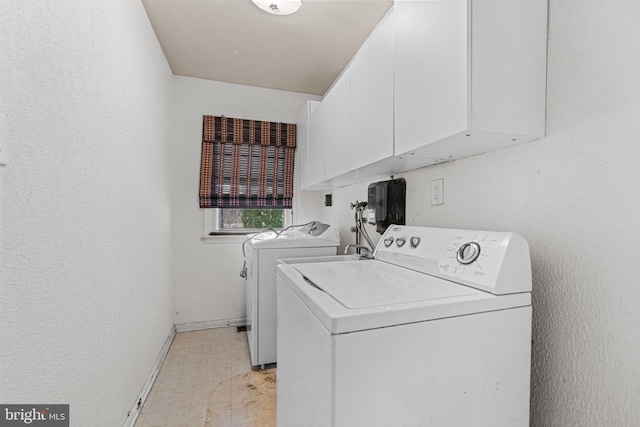 washroom with cabinet space, baseboards, a textured wall, washer and dryer, and light floors