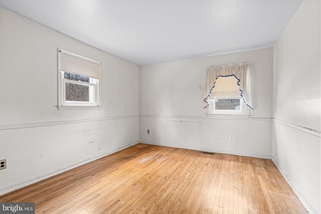 spare room featuring light wood finished floors and visible vents