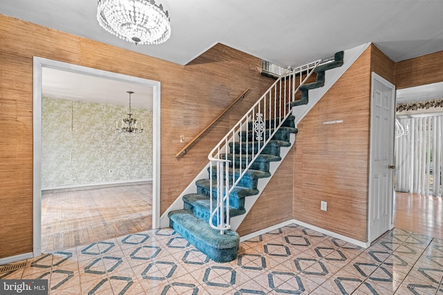 stairs with a chandelier and tile patterned floors