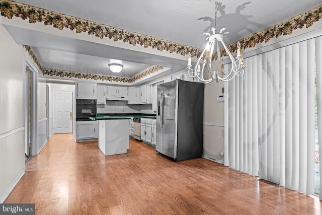 kitchen with light wood-style floors, stainless steel fridge, an inviting chandelier, and oven