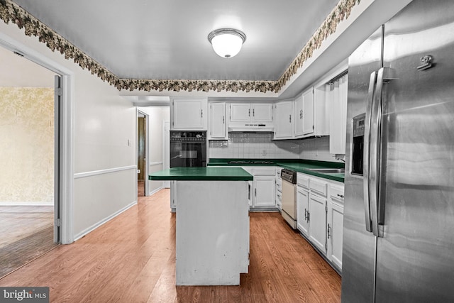 kitchen featuring light wood-type flooring, dark countertops, oven, and stainless steel refrigerator with ice dispenser